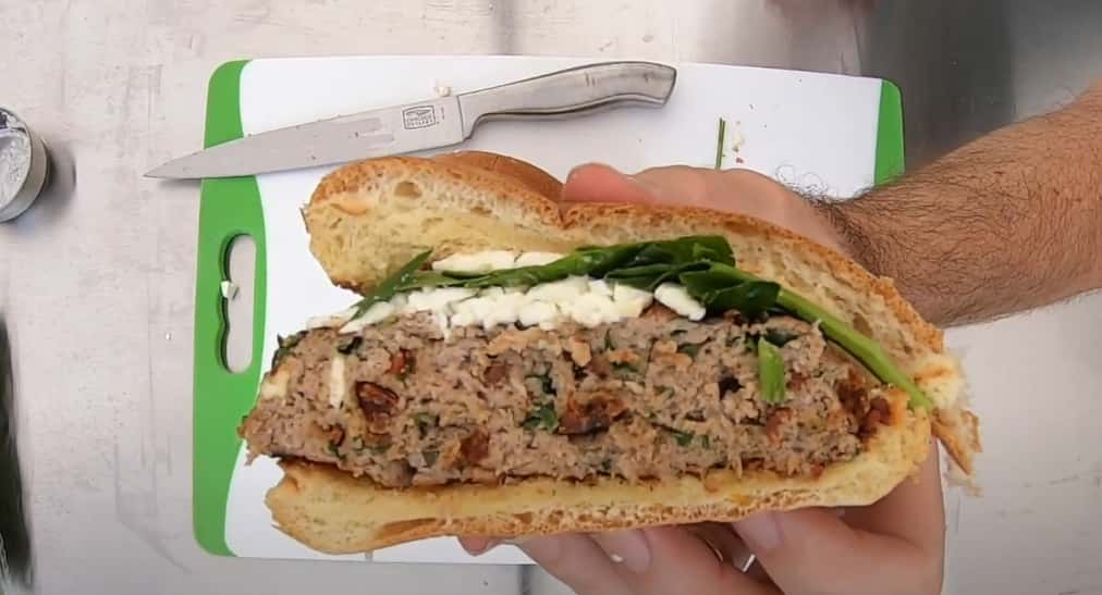 Person's hands holding a sandwich with a thick meat patty