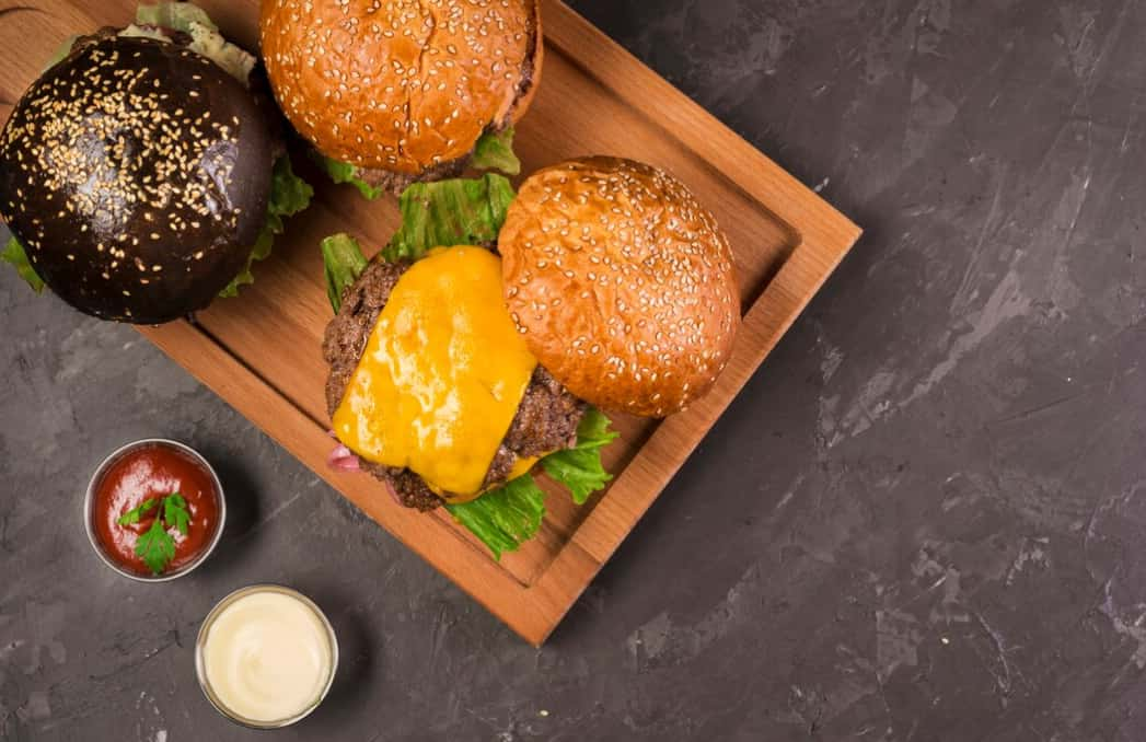 Cooked burgers with cheese on sesame buns with condiments